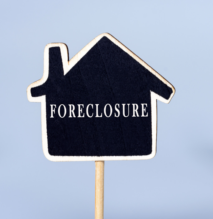 foreclosure sign in the shape of a house on a stick. cute too the point image.